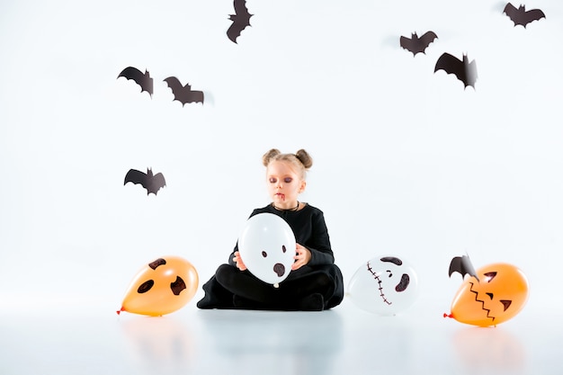 Little girl witch in black long dress and magical accessories