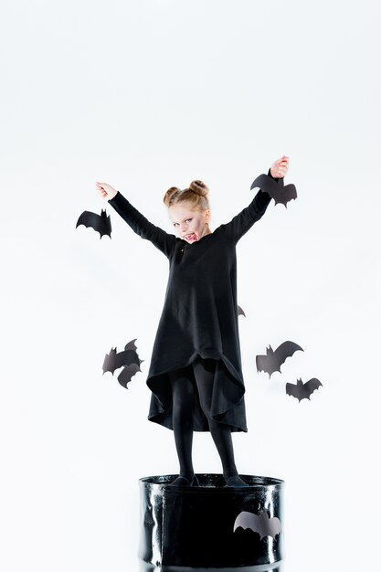 Маленькая девочка-ведьма в черном длинном платье и волшебных аксессуарах.