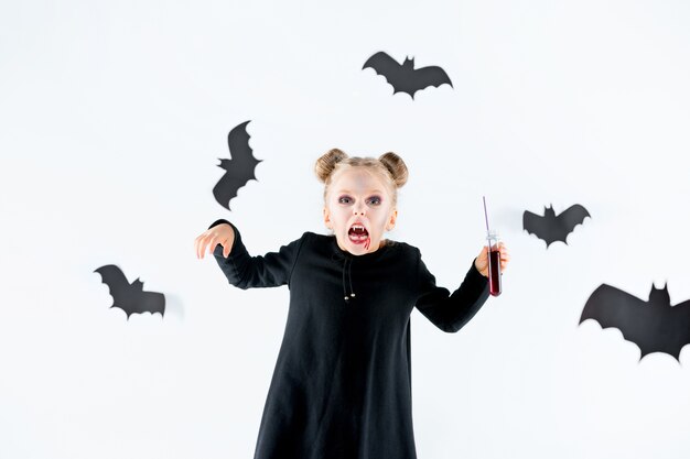 Little girl witch in black long dress and magical accessories.