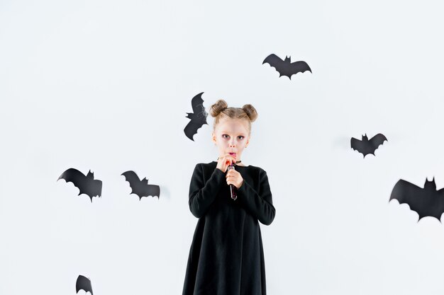 Little girl witch in black long dress and magical accessories.