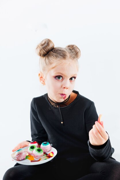 Little girl witch in black long dress and magical accessories