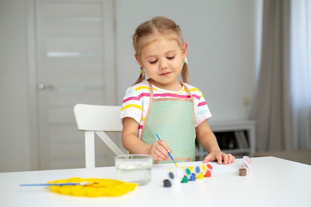 Free photo little girl with apron painting