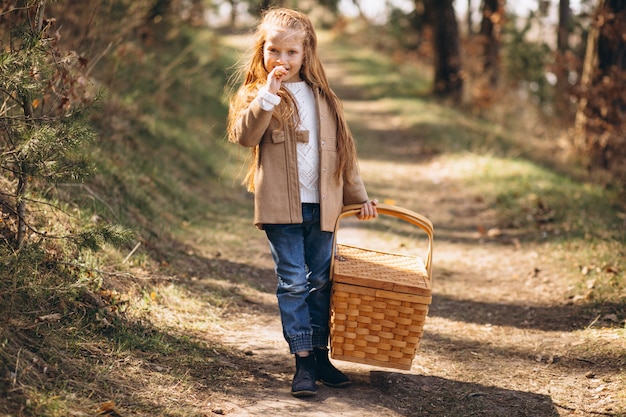 Bambina con grande scatola da picnic nel bosco