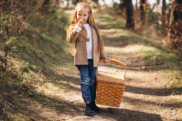 Little girl with big picnic box in the woods