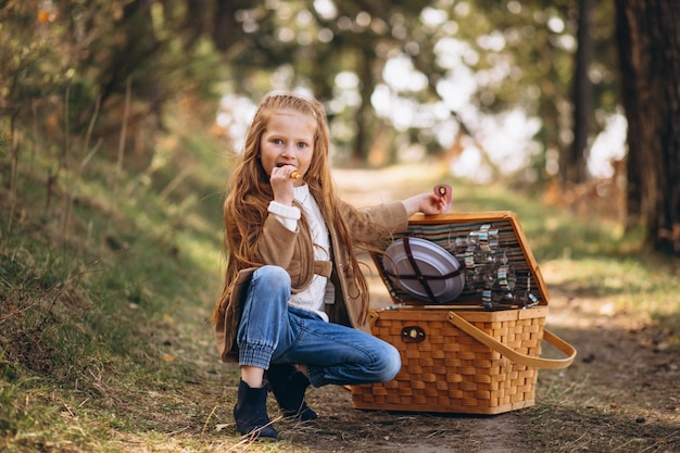 Маленькая девочка с большой коробкой для пикника в лесу