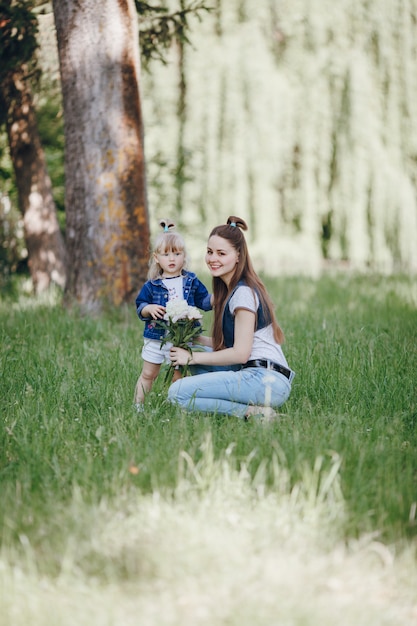 Little girl with a bouquet of white flowers with her mother beside