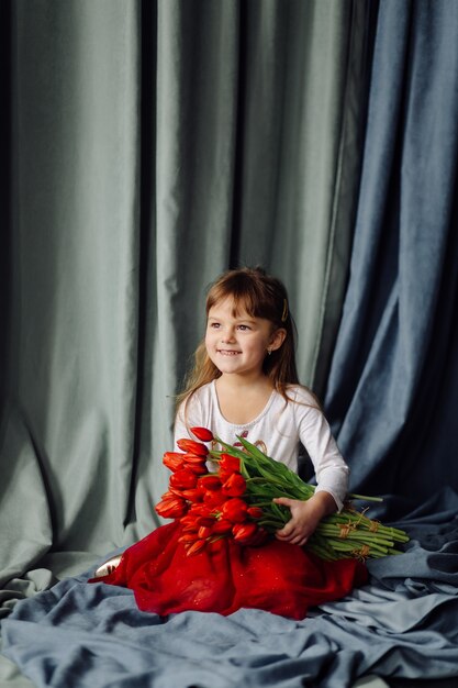 Маленькая девочка с букетом красных тюльпанов