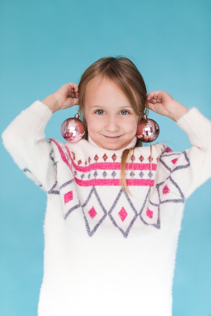 Little girl with christmas ball as earrings