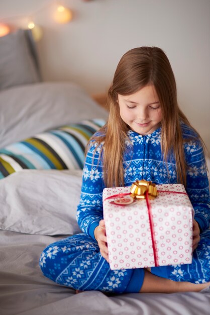 Маленькая девочка с рождественским подарком в постели
