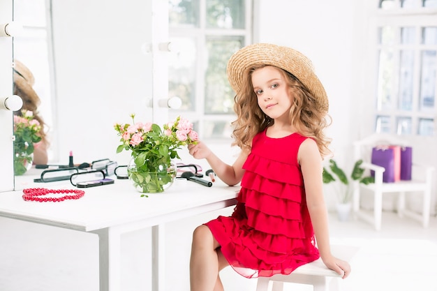 Foto gratuita una bambina con cosmetici. è nella camera da letto della mamma, seduta vicino allo specchio.