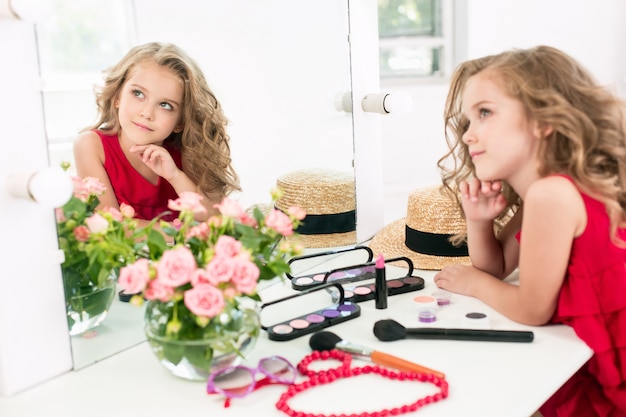 화장품 거울 근처에 앉아있는 어린 소녀.
