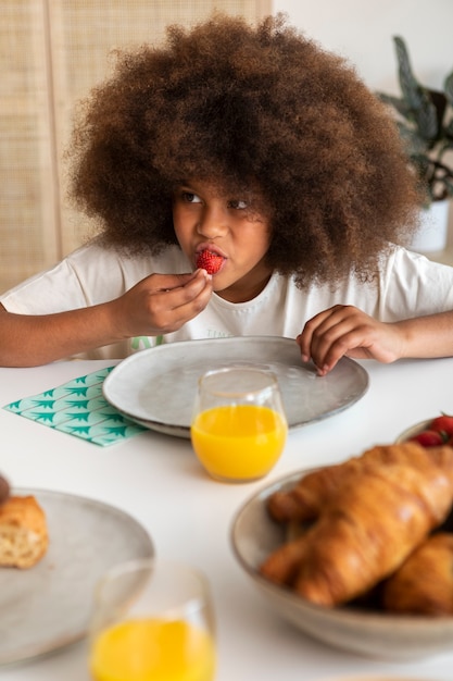 Foto gratuita bambina con capelli ricci che mangia prima colazione