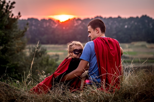 Foto gratuita bambina con papà vestita da supereroi, felice famiglia amorevole