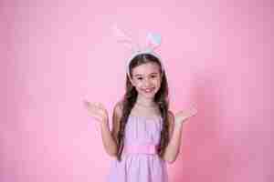 Free photo little girl with easter bunny ears posing on pink