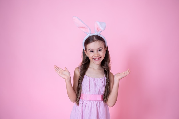 Little girl with Easter bunny ears posing on pink