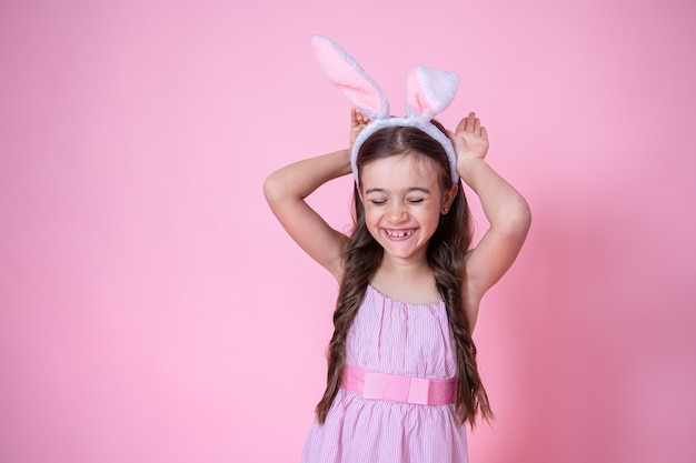 Little girl with Easter bunny ears posing on a studio pink