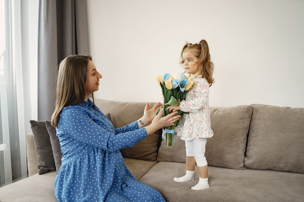 Bambina con fiori. la mamma è incinta. saluti per la mamma.