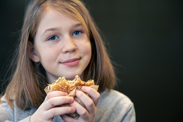 そばかすのある少女がハンバーガーを食べる