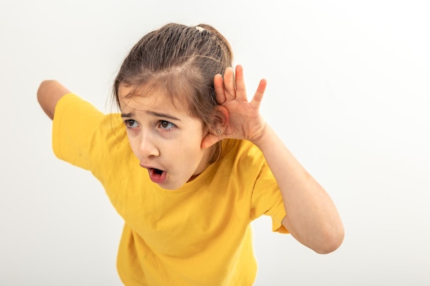 Free photo little girl with hand near ear listening rumor hearing gossip on isolated