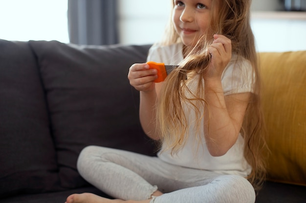 Bambina con i pidocchi che si prende cura dei suoi capelli