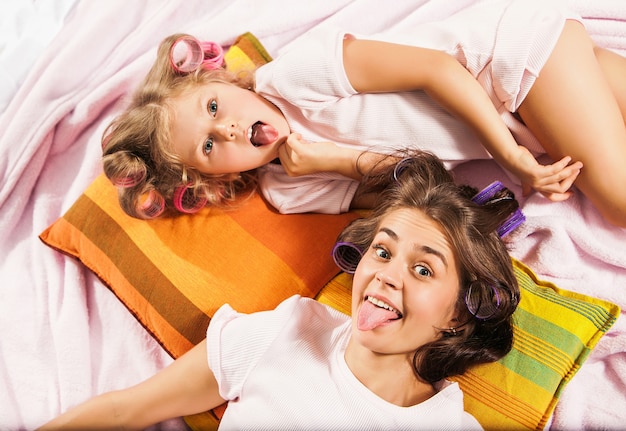 Little girl with her mother playing in bed