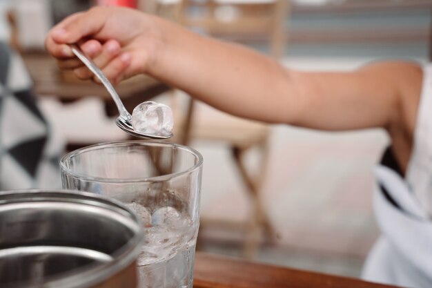 Little girl with mom playing with ice cubes in a cozy cafe. Good relationship of parents and child. Happy moments together