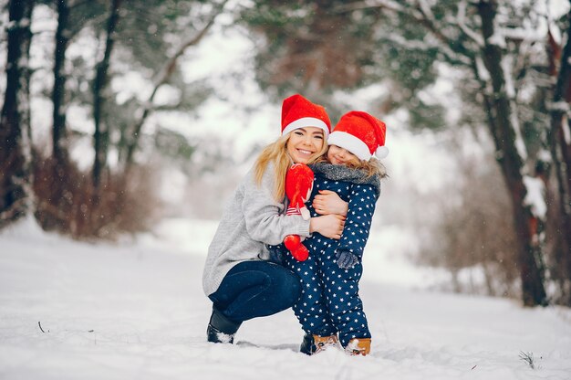 Маленькая девочка с матерью, играя в зимнем парке