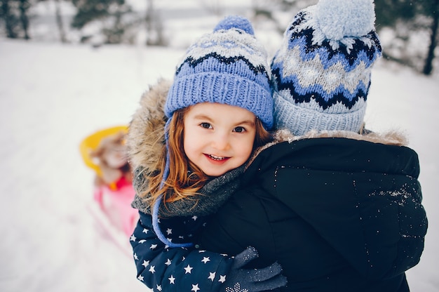 Маленькая девочка с матерью, играя в зимнем парке