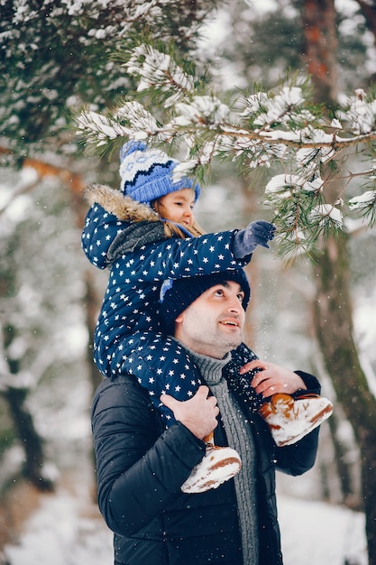 Bambina con i genitori che giocano in un parco d'inverno