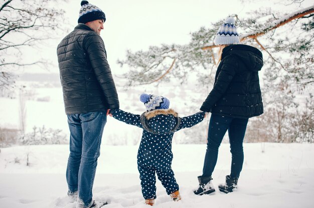 Little girl with parents playing in a winter park