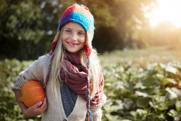 Little girl with pumpkin in the field