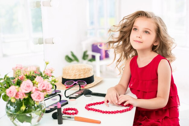 A little girl with red dress and cosmetics.