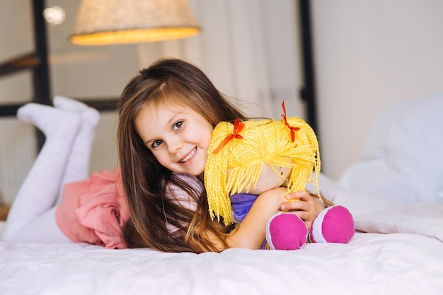Little girl with a toy on the bed health and beauty concept