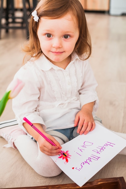 Foto gratuita bambina che scrive happy mothers day su carta