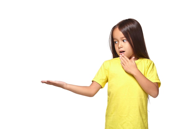 Free photo little girl in yellow t-shirt holding her hand out and showing copy space for your product isolated on white background