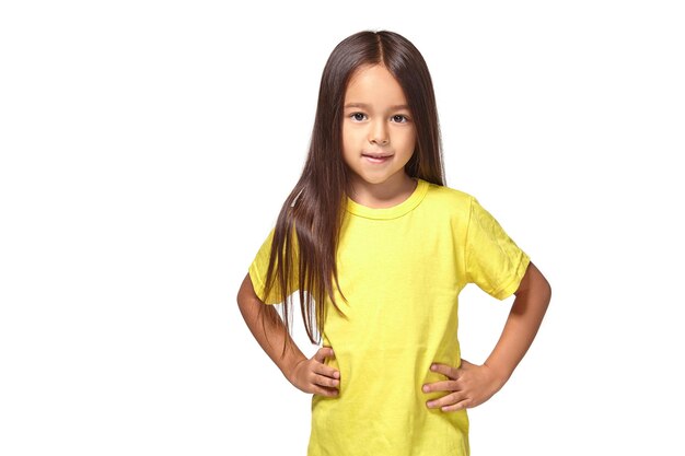 Маленькая девочка в желтой футболке улыбается на белом фоне