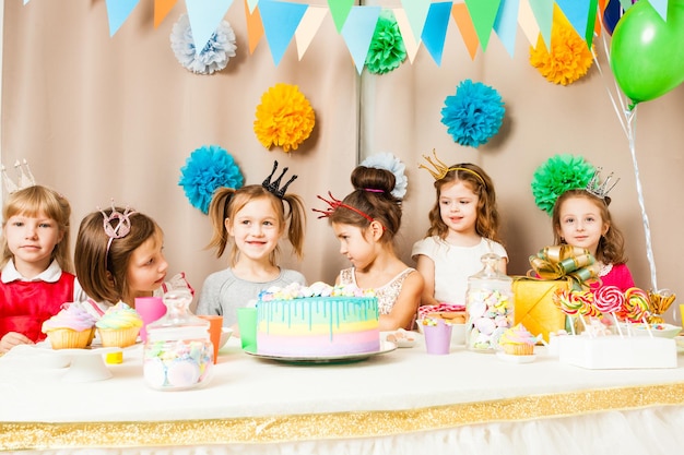 어린 소녀들이 머리에 왕관을 쓰고, 풍선과 맛있는 케이크를 들고 생일을 축하하고 있습니다