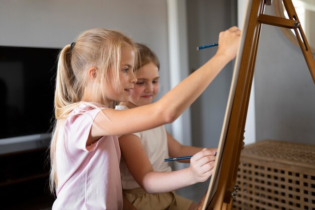 Little girls drawing using easel at home together