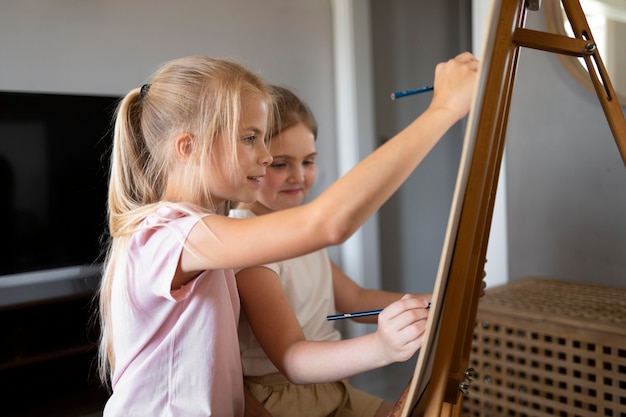Little girls drawing using easel at home together