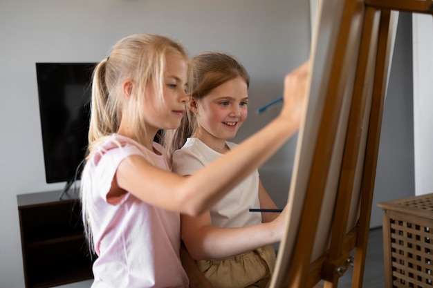 Little girls drawing using easel at home together