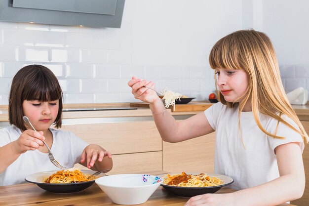 Маленькие девочки едят вкусные спагетти