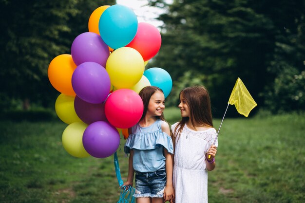 Little girls friends with balloons in forest