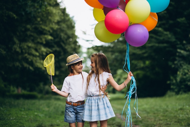 Little girls friends with balloons in forest