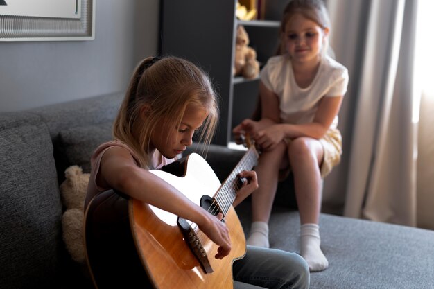집에서 함께 어쿠스틱 기타를 연주하는 어린 소녀