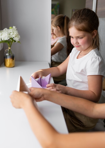 Little girls playing with origami paper at home