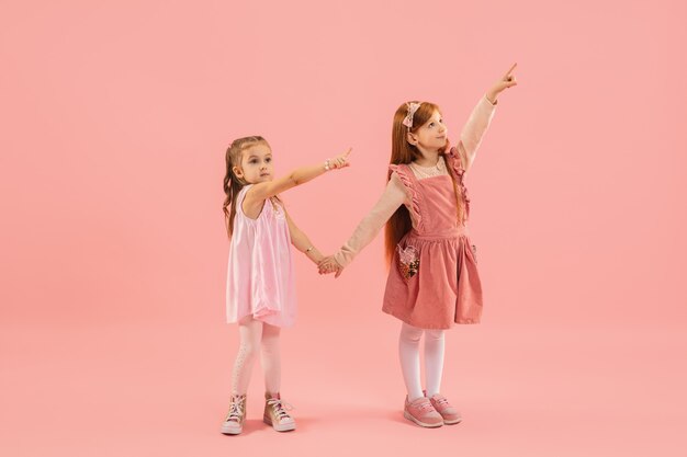 Little girls pointing on pink wall