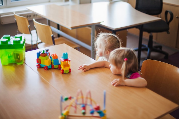 Free photo little girls sitting at table with toys