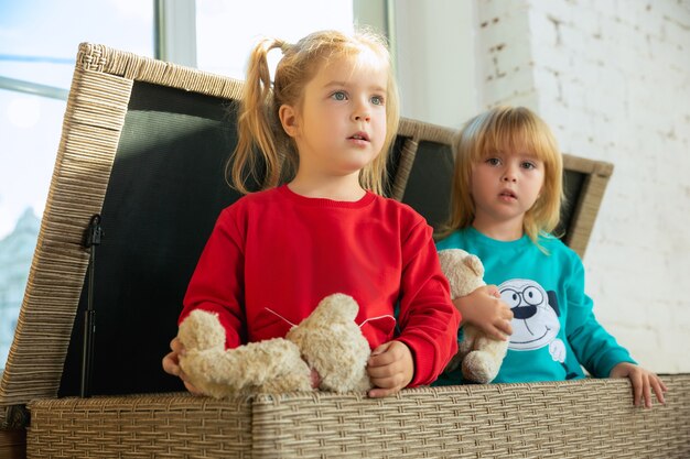 Little girls in soft warm pajamas playing at home. Caucasian children in colorful clothes having fun together.