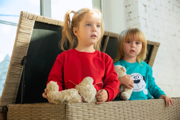 Little girls in soft warm pajamas playing at home. Caucasian children in colorful clothes having fun together.