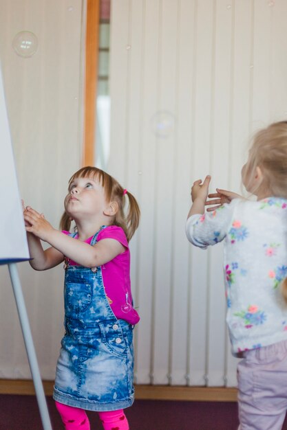 Little girls standing staring at soap bubbles